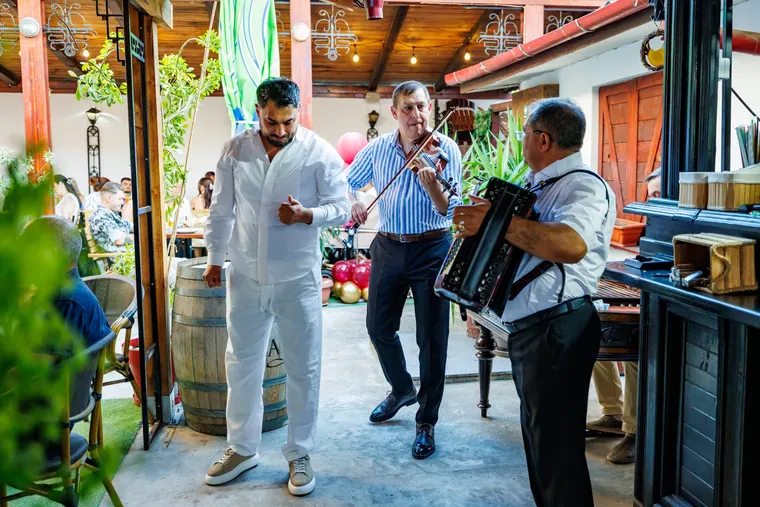 Bărbat care dansează în fața lăutarilor cu vioară și acordeon