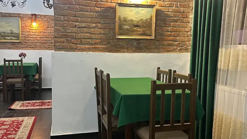 Masă cu față de masă verde, lângă fereastra cu draperie