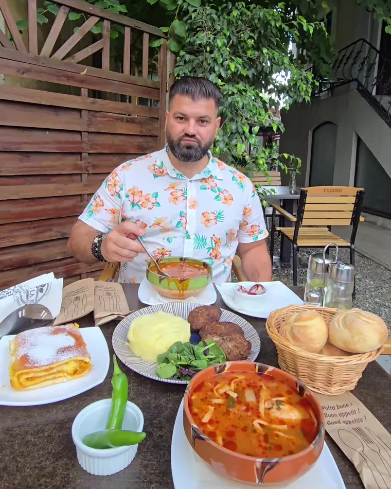 Ion cu o strachină de ciorbă în față, piure, chifle într-un coș și o plăcintă pudrată